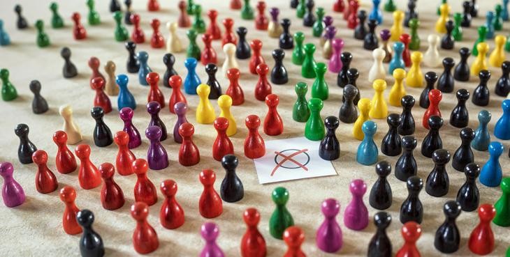 Ein Symbolbild zur Landtagswahl. Spielfiguren in unterschiedlichen Farben stehen um einen Zettel, auf dem ein rotes Kreuz zu sehen ist.