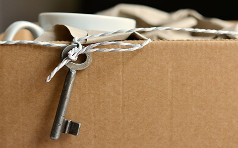 Ein Schlüssel ist an einem Stück Faden befestigt und hängt aus einem Umzugskarton.