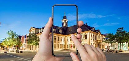 Eine Person hält ein Smartphone vor dem Rathaus in Göppingen.
